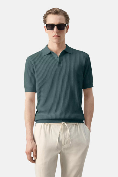 Polo verte MANGO verte, côtelée à manches courtes, vue de dos sur mannequin avec pantalon clair.