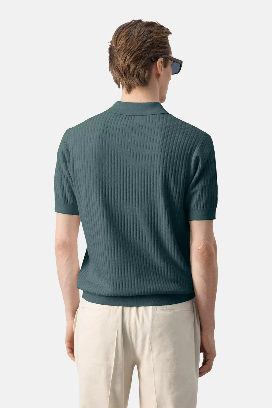 Groene polo van MANGO, geribd met korte mouwen, van achteren gezien op model met lichte broek.