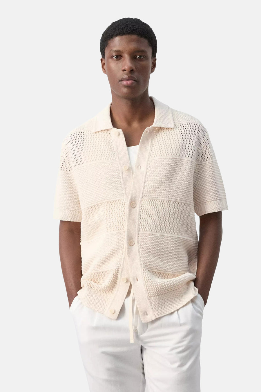 Beige gebreide gilet met knopen en zakken van MANGO, gedragen met witte broek, front view