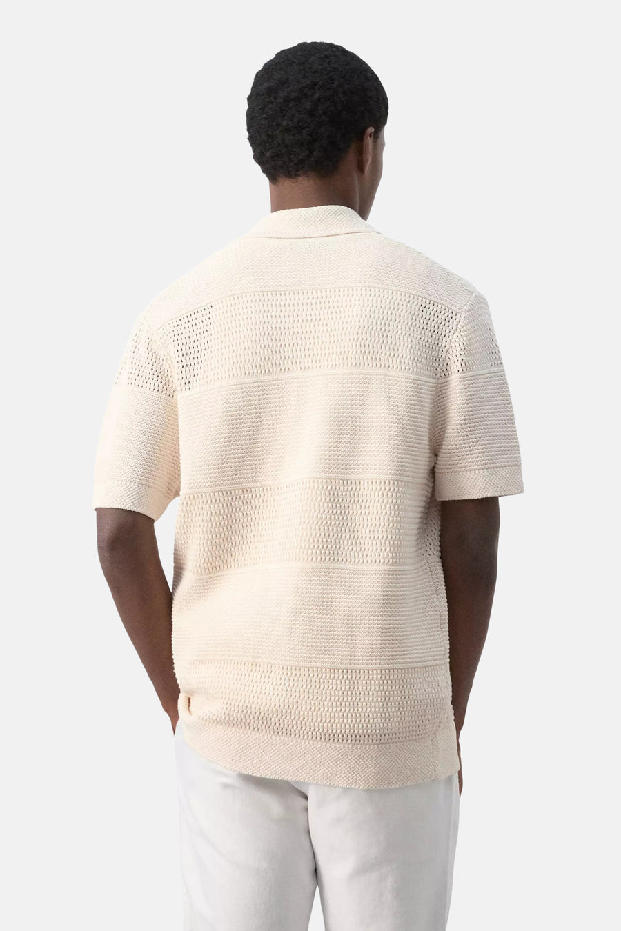 Beige gebreide gilet van MANGO, rugzijde, met horizontale textuurstripes en korte mouwen, gedragen met witte broek