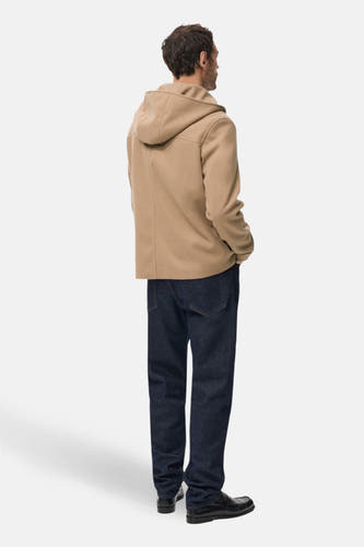 Beige korte jas van MANGO, gezien van achteren, met capuchon, gecombineerd met een donkere jeans en zwarte schoenen.
