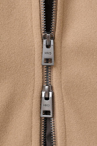 Manteau court beige de MANGO, avec une fermeture éclair métallique et un logo de marque sur la tirette.