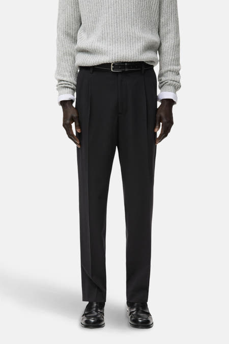 Zwarte broek van MANGO, met plooien, gecombineerd met een grijze trui en leren schoenen.