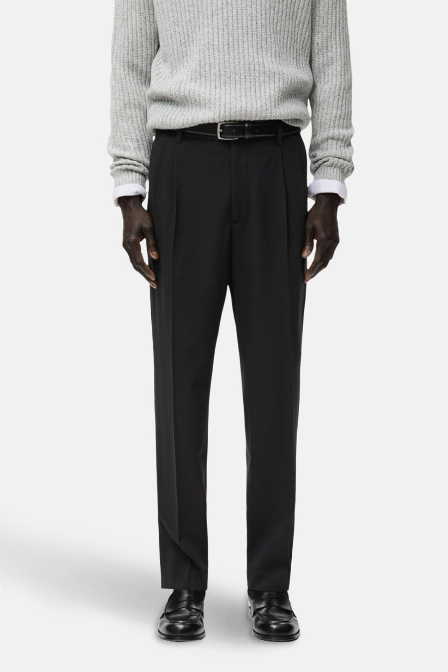 Pantalon noir de MANGO, dos, avec une texture lisse et associé à un pull gris.