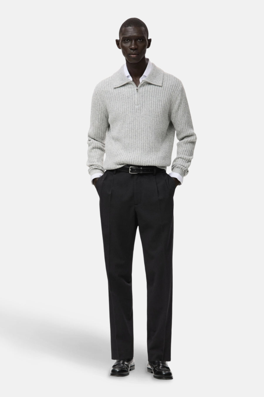 Pantalon noir de MANGO, associé à une chemise grisonnée, un blazer blanc et une ceinture noire avec boucle.