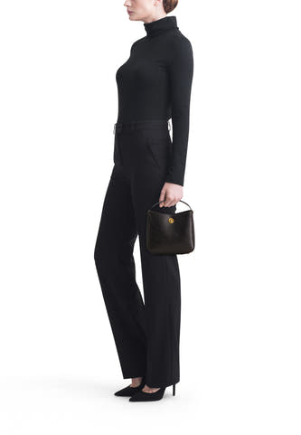 Sac à dos noir de MANGO, porté par un modèle avec une veste et des pantalons noirs.