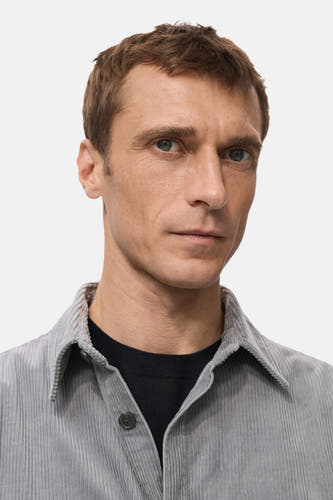 Chemise grise à manches longues de MANGO, avec une texture côtelée et un pull noir en dessous.