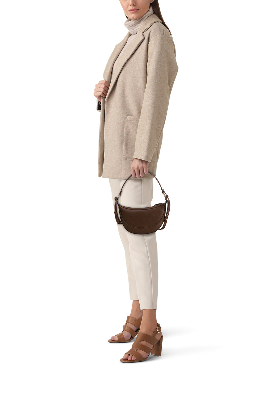 Kaki schoudertas van MANGO, met leren textuur, gedragen met een beige trui en witte pantalon.