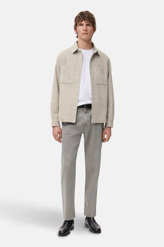 Manteau court beige de MANGO, avec des manches longues et un motif à carreaux, porté sur un T-shirt blanc et des jeans gris.