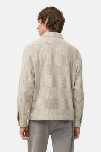 Beige korte jas van MANGO, met een subtiel ruitpatroon en zichtbare knoopsluiting op de mouwen, gezien vanaf de achterkant.
