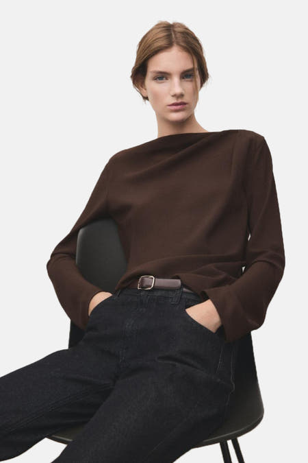Blouse brune à longues manches de MANGO, vue de derrière avec une ceinture brune et des jeans foncés.