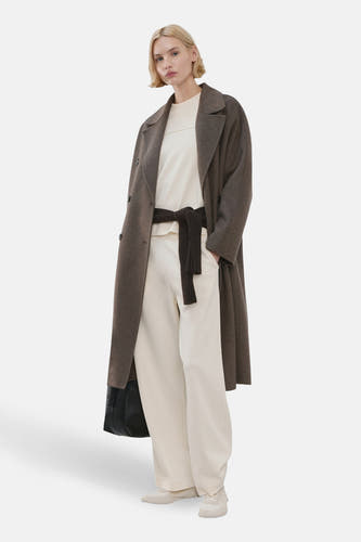 Jean de jogging écru de MANGO, avec des jambes larges et une ceinture marron foncé nouée à la taille.