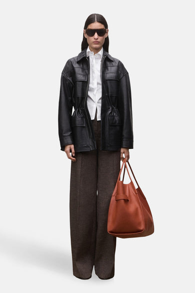 Wit, lang mouwen overhemd van MANGO, gedragen onder een zwarte leren jas met bruine broek en tas.