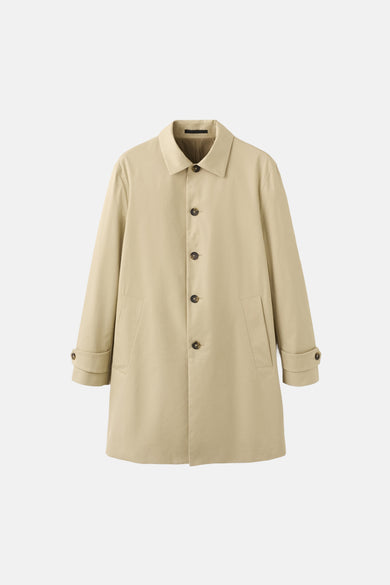 Long manteau beige de MANGO, avec étiquettes à logo et informations sur l'imperméabilité.
