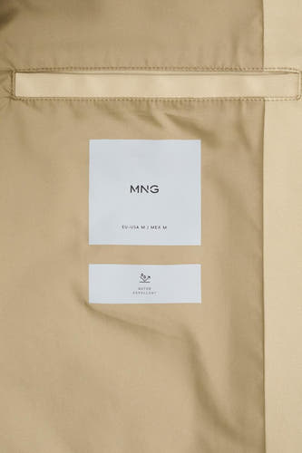 Beige lange jas van MANGO, met labels met logo en informatie over waterafstotendheid.
