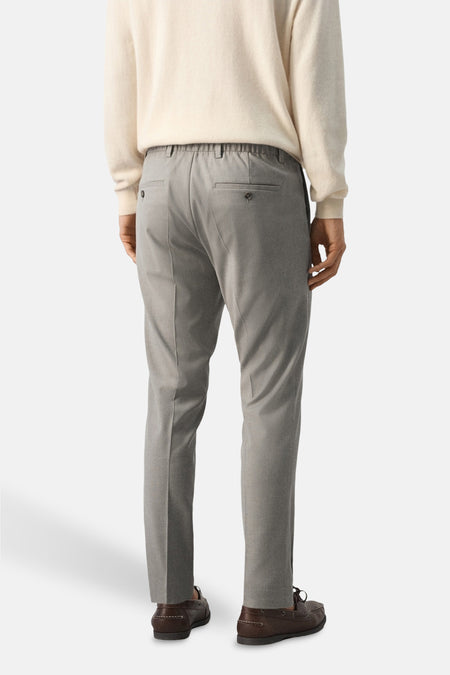 Beige broek van MANGO, gezien van achteren met elastische tailleband en bruine schoenen.
