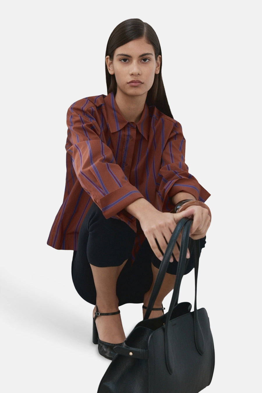 Chemise multicolore de MANGO à rayures verticales bleues, portée avec un pantalon noir et un sac à main.