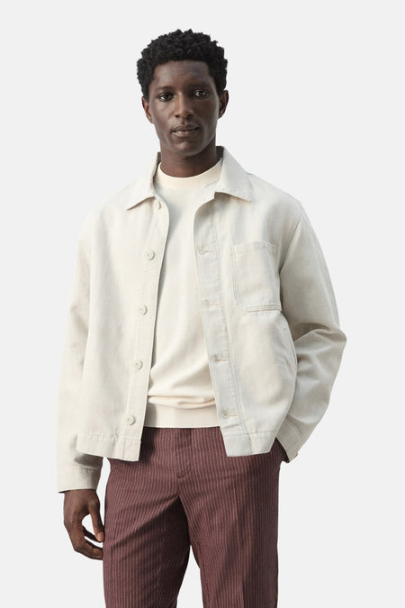 Manteau court écru de MANGO, vu de dos, avec manches longues et pantalon marron.