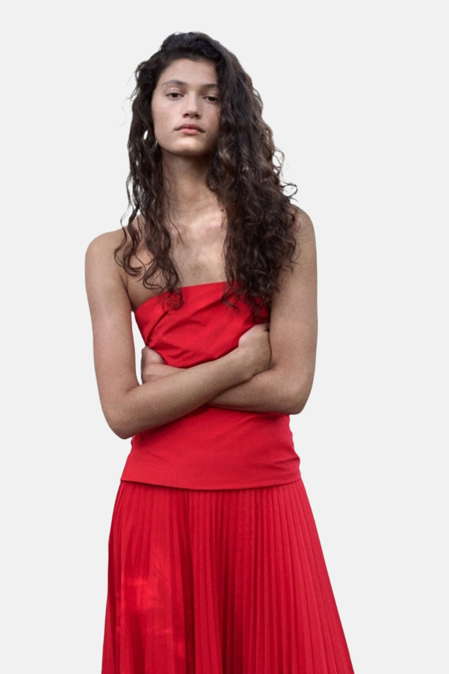 Rood strapless kleedje van MANGO met geplooide rok, gedragen door model met gekruiste armen.
