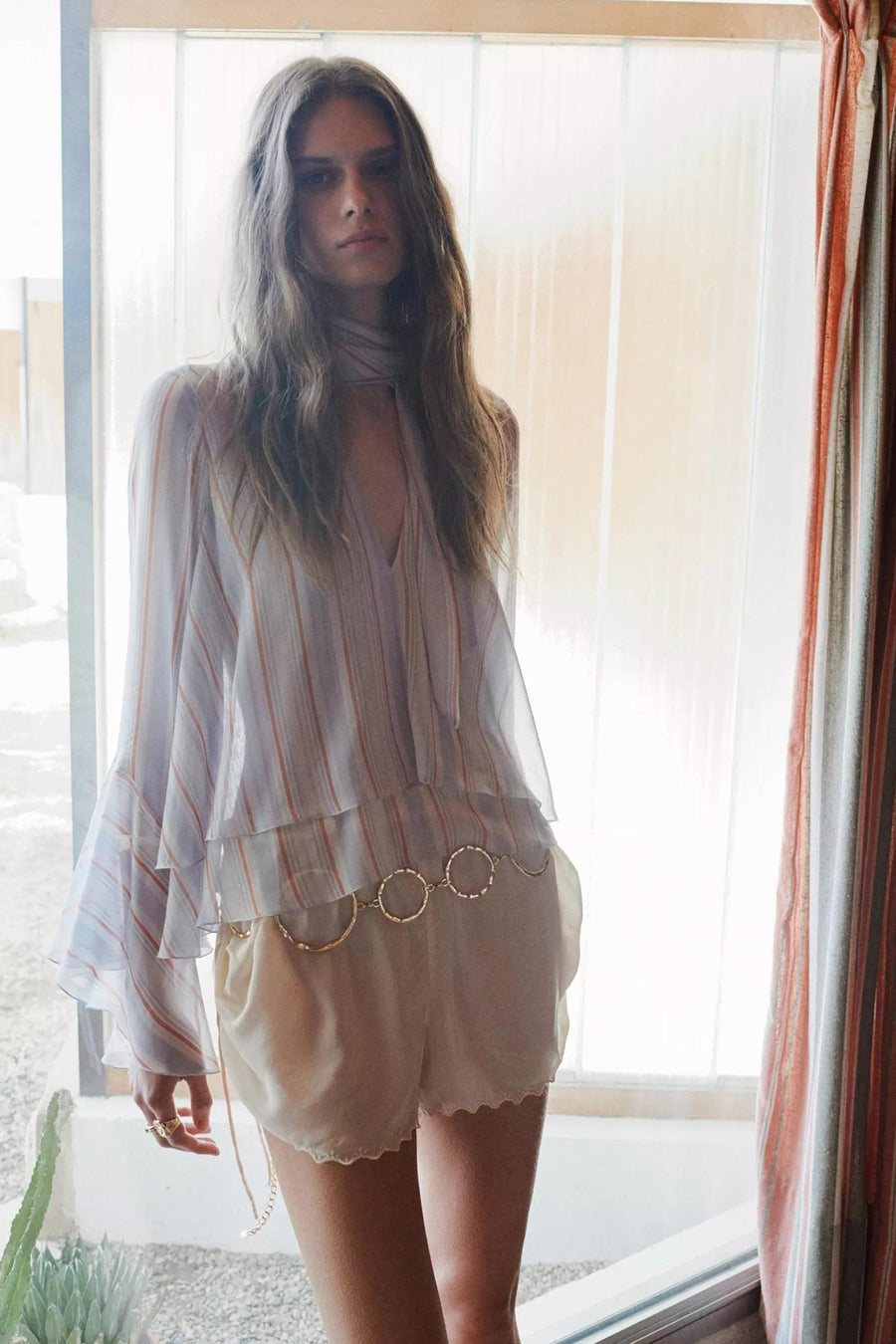 Multicolor gestreepte blouse met ruches en wijde gelaagde mouwen van MANGO, gedragen met lichte korte broek en gouden riem.