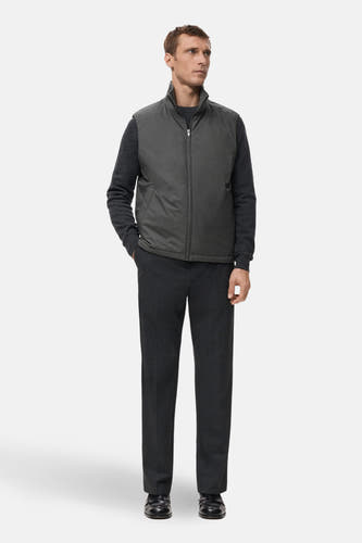 Grijze bodywarmer van MANGO, gedragen over een donkergrijze trui en pantalon, met een rits en steekzakken.
