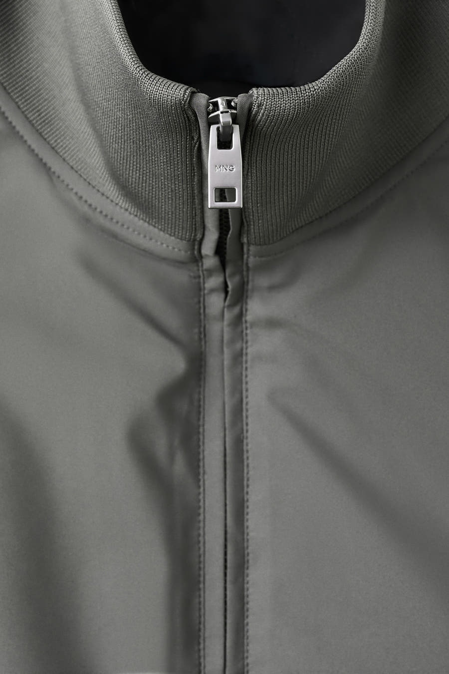 Grijs bodywarmer van MANGO, met een gladde textuur en een zilverkleurige rits aan de voorkant.
