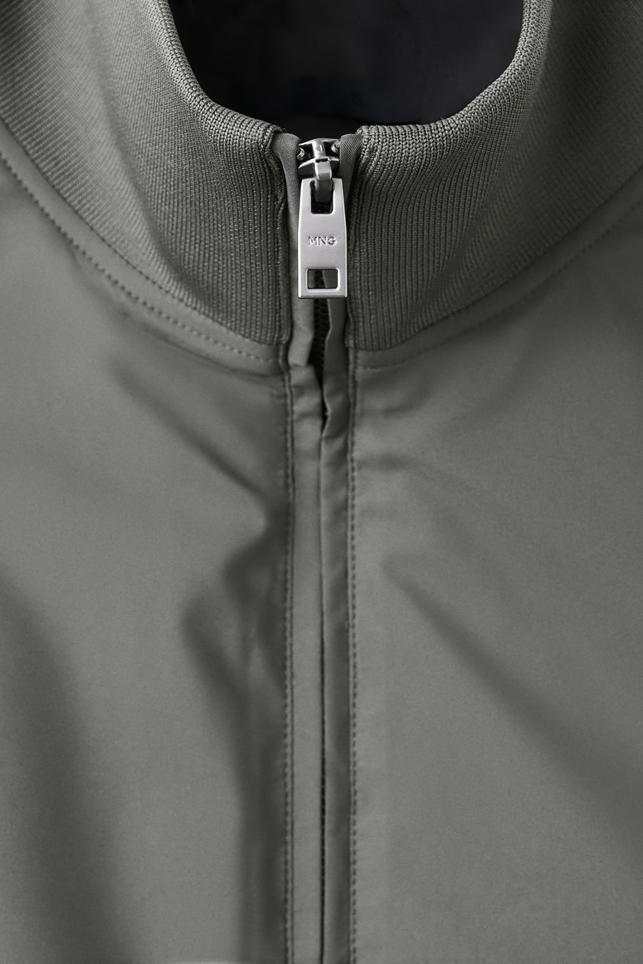 Grijs bodywarmer van MANGO, met een gladde textuur en een zilverkleurige rits aan de voorkant.
