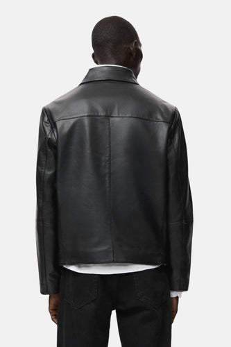 Zwarte korte jas van MANGO, rugzijde getoond, gecombineerd met een wit shirt en zwarte jeans.
