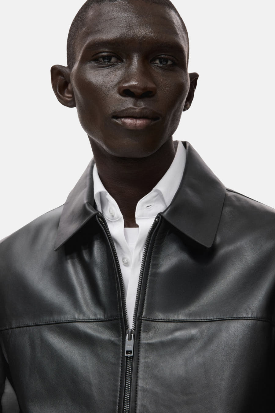 Zwarte korte jas van MANGO met een kraag en een ritssluiting, gedragen over een wit overhemd.