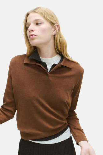 Pull marron avec col rond de MANGO, vu de derrière, avec des cheveux blonds et un manteau dans la main.