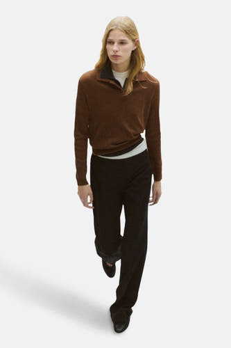 Pull marron de MANGO, avec des manches longues et un col ouvert, associé à une pantalon noir et des chaussures.