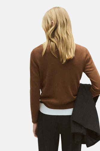 Bruine trui met ronde hals van MANGO, gezien van achteren, met blond haar en een jas in de hand.