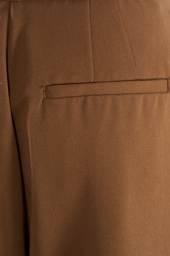 Kakikleurige broek van MANGO, met een klassiek paspelzakdetail op de achterkant.
