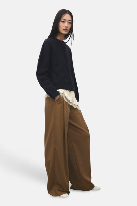 Kaki broek van MANGO, met wijde pijpen en een nonchalante pasvorm, gecombineerd met een wit kanten topje en donkerblauw vest.