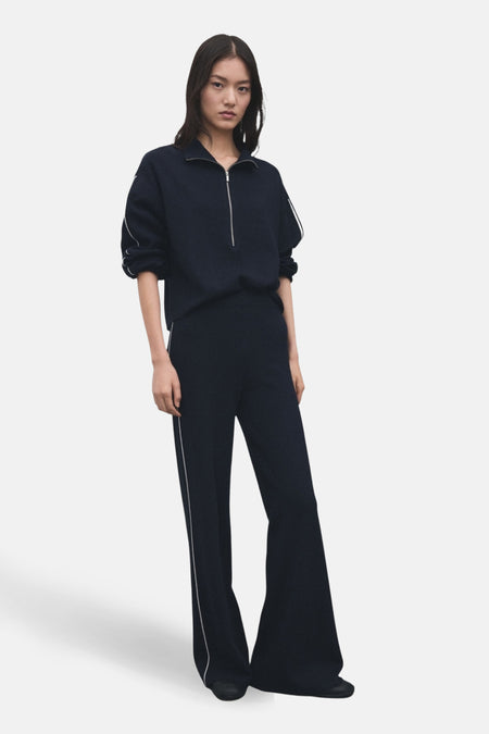 Vrouw in donkerblauwe sportieve kleding met witte accenten, staand.