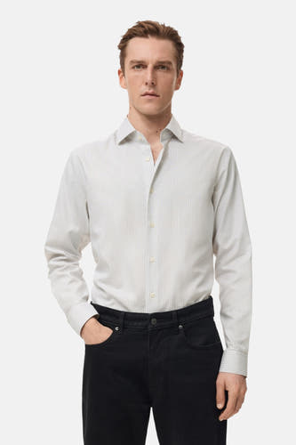 Chemise grise à manches longues de MANGO, avec un motif rayé et un pantalon noir.