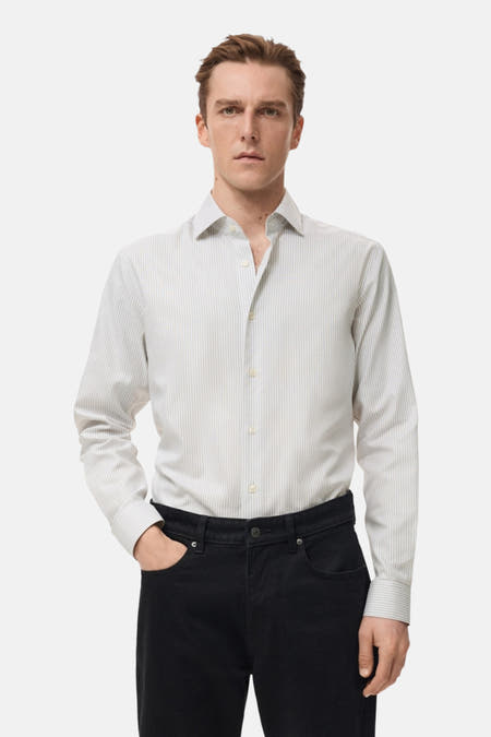 Grijs overhemd met lange mouwen van MANGO, gestreept dessin en zwarte jeans.
