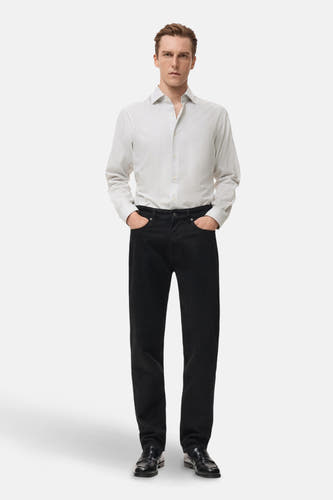 Chemise grise à manches longues de MANGO, avec un motif à fines rayures, portée avec des jeans noirs et des chaussures en cuir.