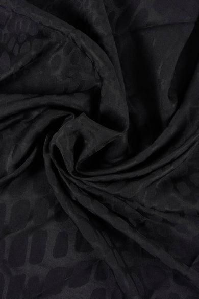 Zwarte zomersjaal van MANGO, met een subtiel patroon en elegante drapering.