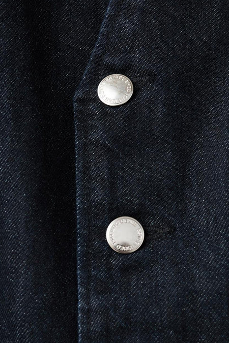 Donkerblauw denim jumpsuit van MANGO, met zilverkleurige knopen als detail.
