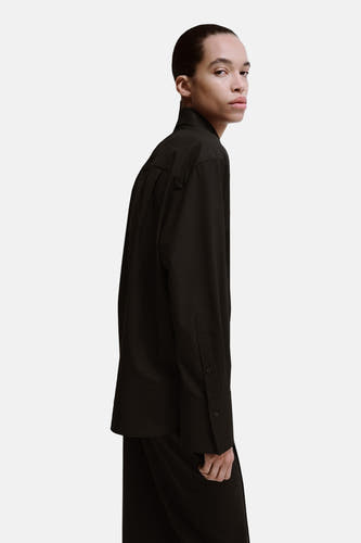 Bruin hemd met lange mouwen van MANGO, close-up zijzicht van een model met een effen outfit.

