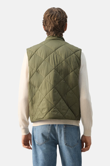 Groene bodywarmer van MANGO met ruitstiksel, gedragen over een crèmekleurige trui en blauwe jeans, rug aanzicht.
