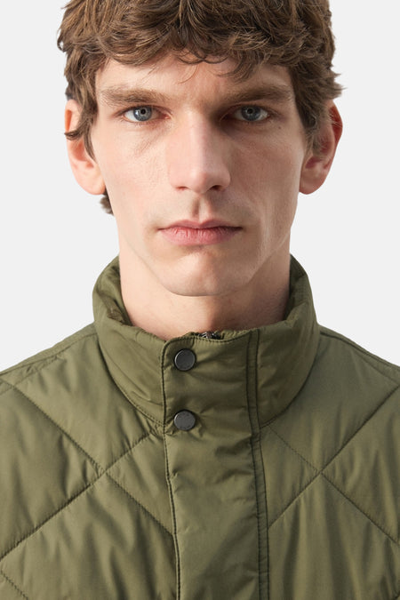 Groene bodywarmer van MANGO met een diamantvormig stiksel en knoopsluiting.
