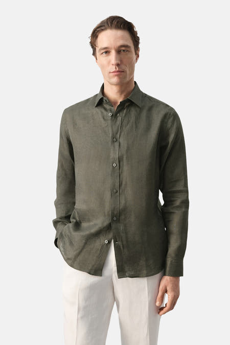 Chemise kaki à manches longues de MANGO, vue de dos, avec un motif uni et un pantalon de couleur crème clair.