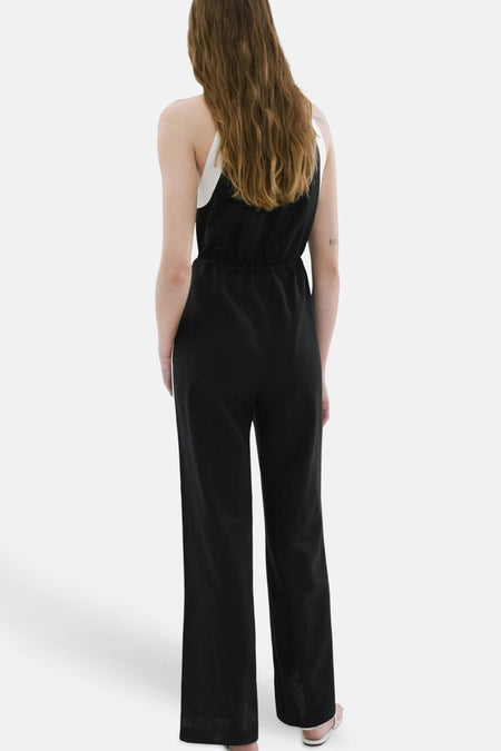 Zwarte jumpsuit met witte bandjes van MANGO, van achteren gezien met elastische taille en wijde pijpen.