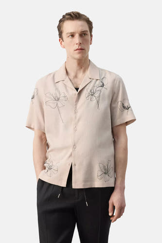 Beige korte mouwen hemd van MANGO met bloemenprint, reverskraag, gedragen met een zwarte broek.
