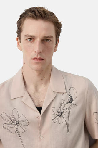 Beige hemd met korte mouwen van MANGO, met open kraag, lichte textuur en abstracte zwarte bloemborduursels.
