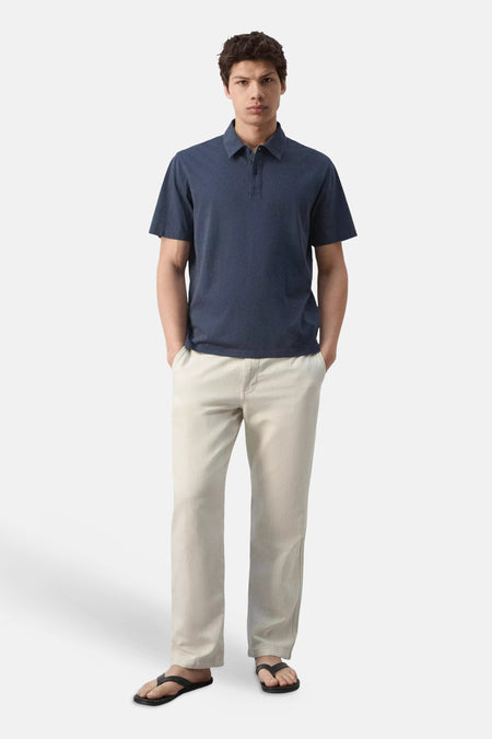 Polo bleue de MANGO à manches courtes, portée par un homme en pantalon clair, vue de dos.