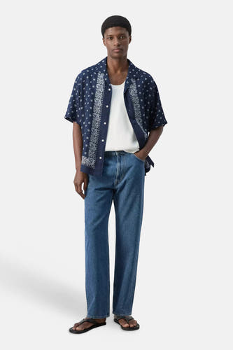 Blauw hemd met korte mouwen van MANGO, met wit paisley- en ruitjespatroon, open gedragen over een wit onderhemd.