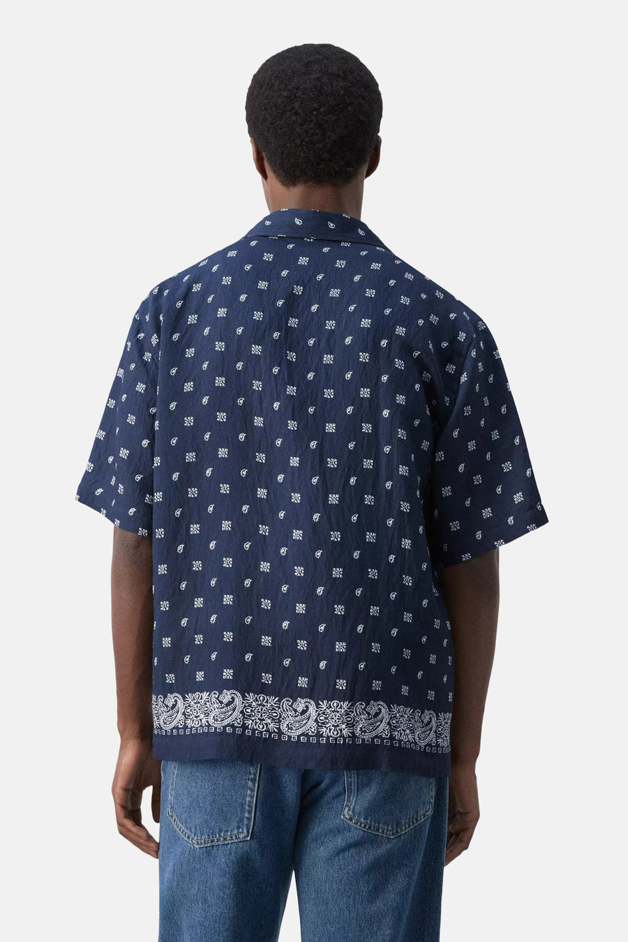 Blauw overhemd met korte mouwen van MANGO, met witte paisley en geometrische patronen, rugaanzicht, gedragen door een man met jeans.